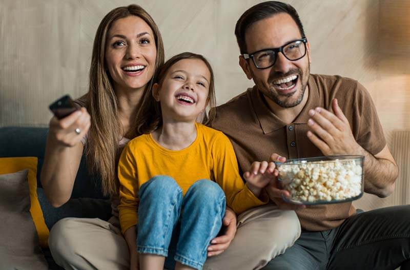 Family-laughing-watching-TV Mother and young daughter laughing while watching TV